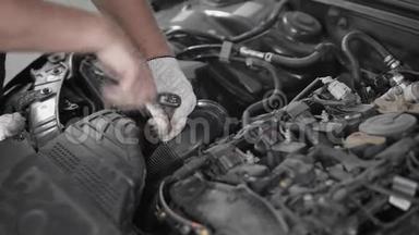 一名专业汽车修理工在汽车引擎盖下固定一部分，固定汽车发动机的特写镜头。