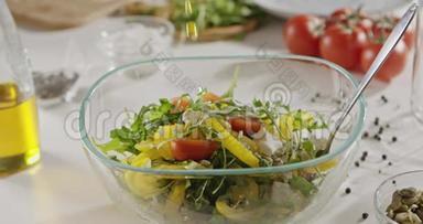 橄榄油是用勺子倒入一个玻璃碗，里面有机蔬菜、奶酪和南瓜籽沙拉。 慢动作