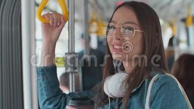 年轻时尚的女人在现代电车上享受旅行，站在公共交通工具上喝咖啡。