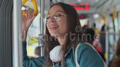 年轻时尚的女人在现代电车上享受旅行，站在<strong>公共交通工具</strong>上喝咖啡。