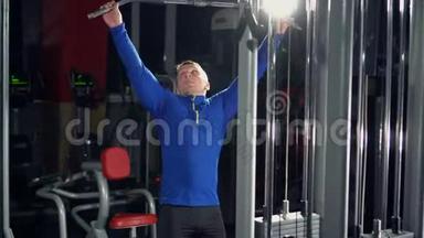 在健身房训练三头肌手。 那个人在健身房举重。 强壮的运动员。 重型列车