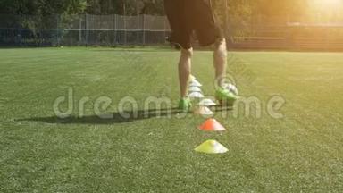 足球场腿技能训练.. 足球运动员在足球场上奔跑，在球锥之间领先