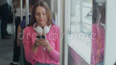 年轻快乐的女人在旅行中坐在靠近窗户的<strong>公共交通工具</strong>上使用智能手机。