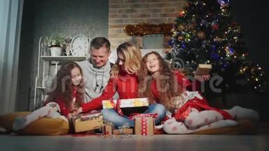 幸福的四口之家正微笑着望着圣诞树脚下的摄像机
