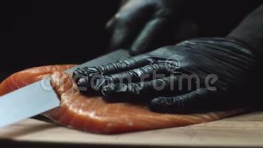 在<strong>寿司</strong>吧里，在手套里为<strong>寿司厨师</strong>切鲜鲑鱼。 切割三文鱼片