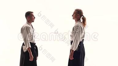 两个穿和服的男人练习合气道的技巧，被隔离在白色上。 快关门。 慢动作。