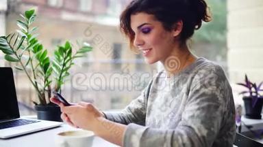 美丽的年轻<strong>女子</strong>在咖啡<strong>馆</strong>里用她的手机和微笑的特写镜头。 在咖啡<strong>馆</strong>里使用智能手机的女人
