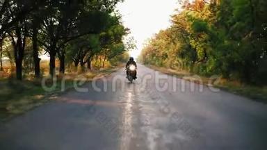 在阳光明媚的日子里，穿着黑色头盔和皮夹克的男士骑摩托车在柏油路上的正面景色
