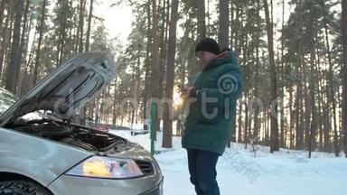 冬天，一个人修理一辆破汽车。一名男子站在打开的汽车引擎盖旁，正在寻找破损处。