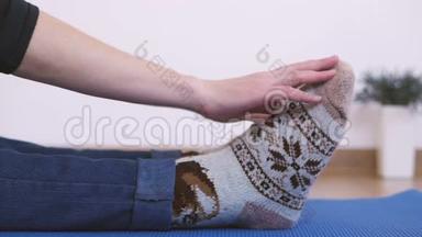 一个穿暖和针织袜子的女人做早操，而坐着把手指伸到脚趾上。