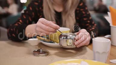 一个身份不明的女人用勺子往餐馆的杯子里倒糖。慢动作