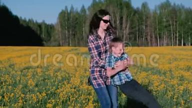 <strong>妈妈</strong>和儿子正在用黄花<strong>牵</strong>着<strong>手</strong>在田野上旋转。 家人在春天散步。