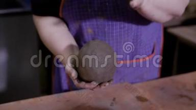 一位陶艺大师的手用粘土捏成了一个大球`近距离拍摄。