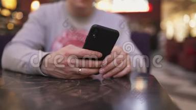 一位年轻的商人坐在咖啡馆的桌子旁，用iphone和短信打字——成功人士，每天