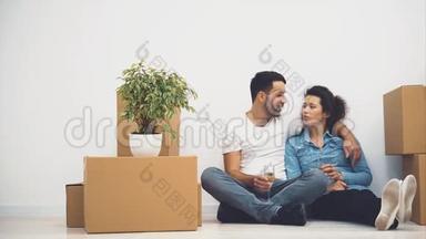 幸福的一对夫妇坐在地板上，拿着一杯白葡萄酒。 行动。 4K.