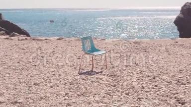 在海滩上靠海的椅子。 库存。 古老的孤椅矗立在石滩上，映衬着蔚蓝美丽的大海和晴空