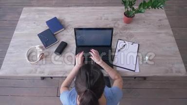 女学生在笔记本电脑键盘上输入文字，在网上学习时在桌上的剪贴板上写笔记