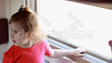 小女孩乘火车旅行。 婴儿乘火车旅行，看着窗外。