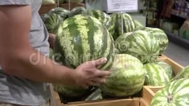 主题养生与天然<strong>美食</strong>.. 一个高加索人的特写`他的<strong>手</strong>握着，在超市的盒子里挑选一个西瓜。