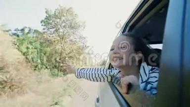 年轻的女人感觉风通过车窗。 向车窗外倾斜的女孩