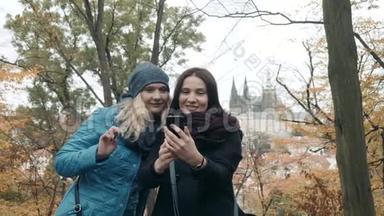 两个美丽快乐的年轻女子在秋天的公园里用手机做<strong>小生</strong>活。 最好的朋友做自我