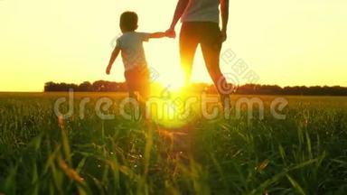 日落时分，母亲和孩子在绿草上散步。 妈妈牵着男孩的手，但他不想和她一起去