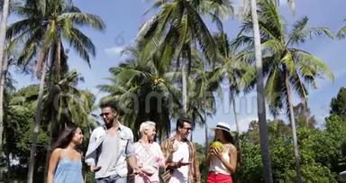 人群群聊抱着椰子走户外棕榈树，快乐的微笑混合了种族男人和女人