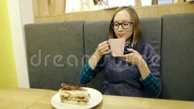 戴眼镜的快乐女孩喝着红茶，喝着蓝莓和薄荷，从一个粉红色的<strong>大杯子</strong>里拿出来，在咖啡馆里放松