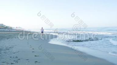 这个女孩从事运动。 她沿着海滩在摄像机上奔跑。