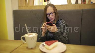 悲伤的女人在咖啡馆里使用智能手<strong>机上</strong>的应用程序，喝着带棉花糖的热巧克力，在手<strong>机上</strong>发短信。 同时
