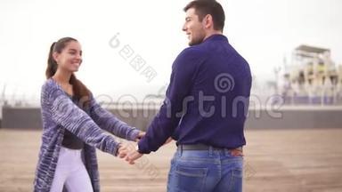 在海滩上，一对年轻夫妇手牵着手，一起散步，看着眼睛，开心地笑着
