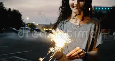 快乐微笑的女孩在夜色中燃烧着火花，身后是不聚焦的城市灯光