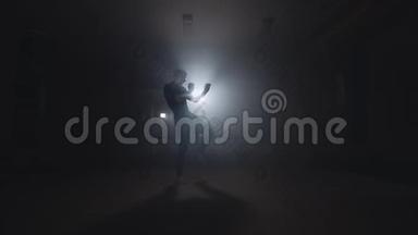 运动员在烟雾缭绕的演播室里拳击。深色背景的剪影。拳击训练