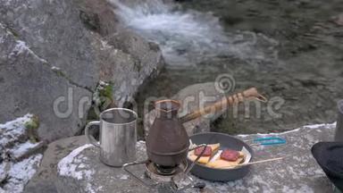 在便携式燃气燃烧器上有一个水壶。 咖啡被扔进里面。 山河附近野餐.. 特写