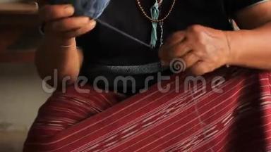 当地的卡伦·斯加夫山区部落的一名妇女，在准备手工编织传统服装和CRA时，滚动一个蓝色染色线球
