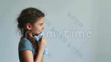 女孩在灰色背景上打喷嚏成手帕。 小女孩感冒了，吹鼻子。 少女感冒