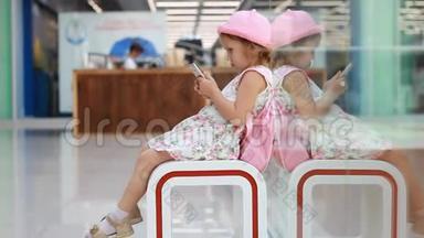 在机场候机楼里坐在等候室里的儿童游客在等待他们的时候玩手机