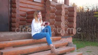 坐在木<strong>屋</strong>门廊台阶上喝<strong>茶</strong>的年轻女子