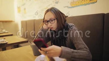 一个沮丧的年轻不耐烦的女孩戴着眼镜错过了咖啡馆。 那个疲惫的女人正在等男朋友，很无聊