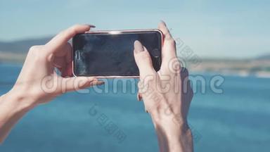 在海滩的地平<strong>线上</strong>，一位女士用智能手机相机拍照。 年轻女孩拍照