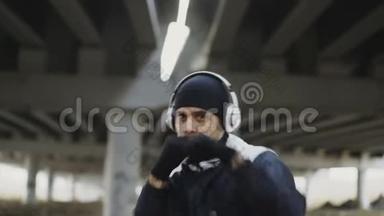 冬季在城市户外进行拳击运动时戴耳机的运动男拳击手特写镜头