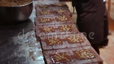 巧克力工厂，制作巧克力的过程.. 将液体巧克力倒入形式中，加入坚果并冷却