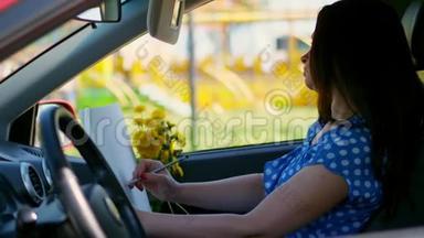 艺术家，美丽的黑发女人，坐在车里，画<strong>铅笔素描</strong>，画一束黄色的蒲公英。 由