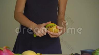 慢镜头拍摄一位年轻女子剥芒果和许多热带<strong>水果</strong>放在<strong>桌子上</strong>