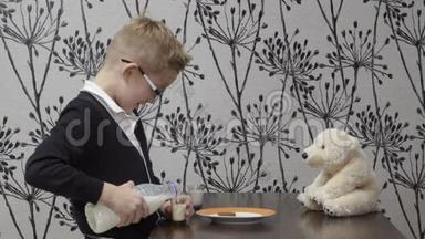 有趣的男孩和他的朋友玩具熊一起喝牛奶