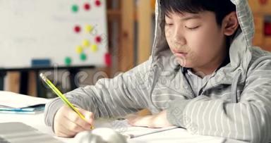 愤怒的亚洲男孩做你的家庭作业，感到焦虑，担心和疲倦。 多莉向左向右移动。