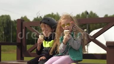 一个<strong>男</strong>孩和一个女孩坐在公园的长凳上吃冰淇淋。 <strong>夏季</strong>