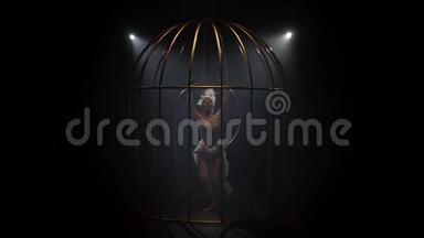 体操运动员在一个金笼里的箍上旋转。 <strong>黑烟</strong>背景