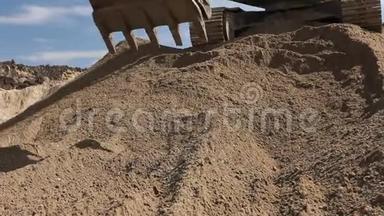 挖掘机正在准备一堆沙子，以便在建筑工地的卡车上装载