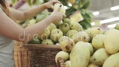 女人在超市挑选绿色芒果。 一个从杂货店拿芒果的女人。 女孩选择
